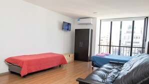 A room with a bed, a sofa, a wardrobe, and a window with a city view. - Rosario Center (Rosario)