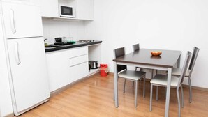 A compact kitchen with white cabinets, a microwave, a stove, and a dining table with four chairs. - Rosario Center (Rosario)