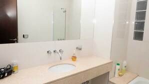 A bathroom with a white sink, a mirror, a shower, and a toilet. - Rosario Center (Rosario)