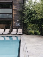 Una piscina al aire libre, sombrillas, sillones reclinables de piscina