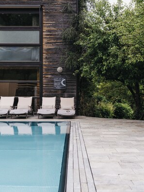 Un área de piscina con sillones de descanso y una terraza de madera.