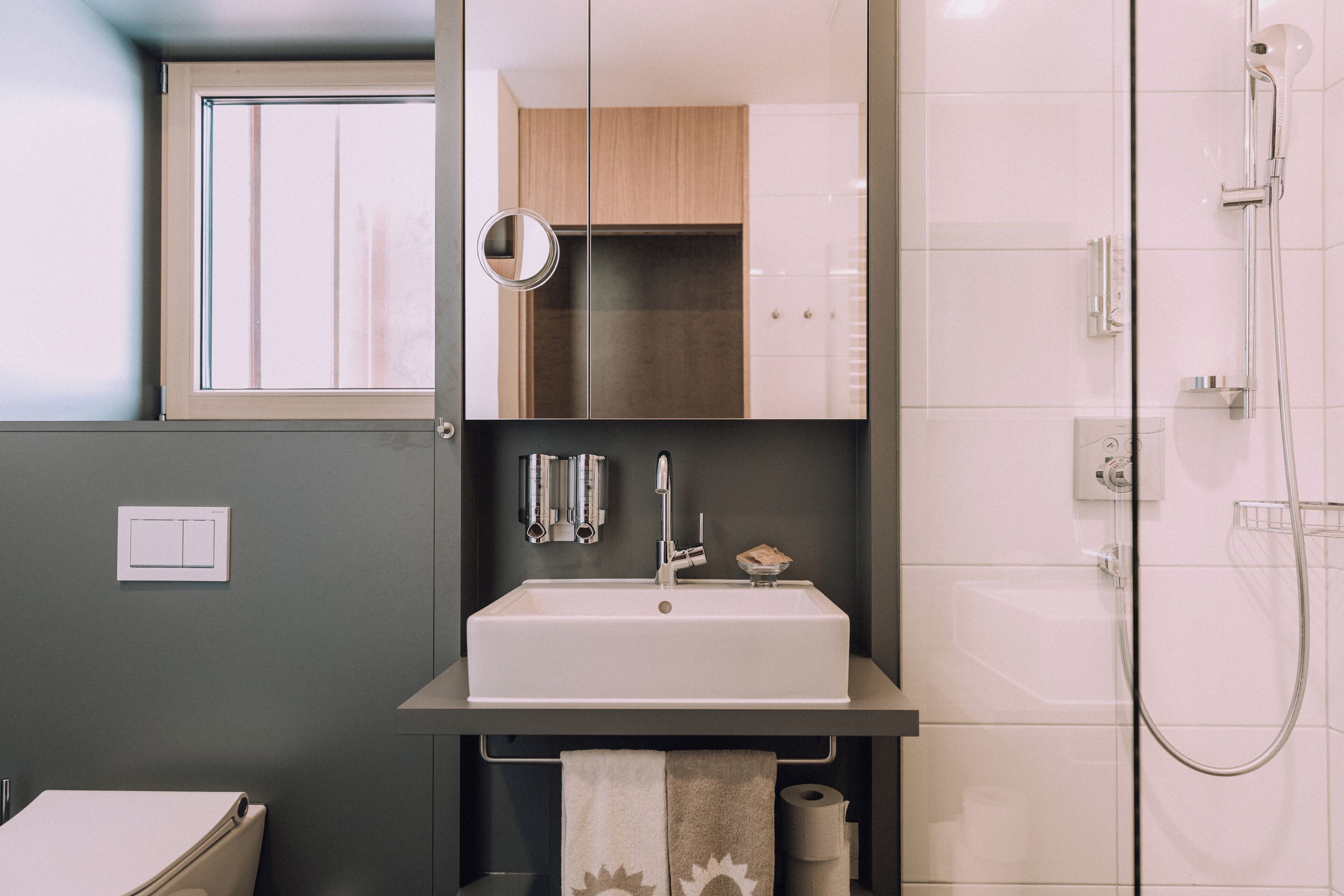 Uma casa de banho moderna com um espelho grande, uma pia e um chuveiro.