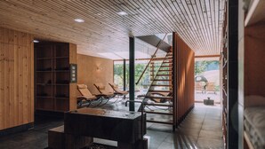 Un interior moderno con techo de madera, una escalera y un área de estar con sillas.