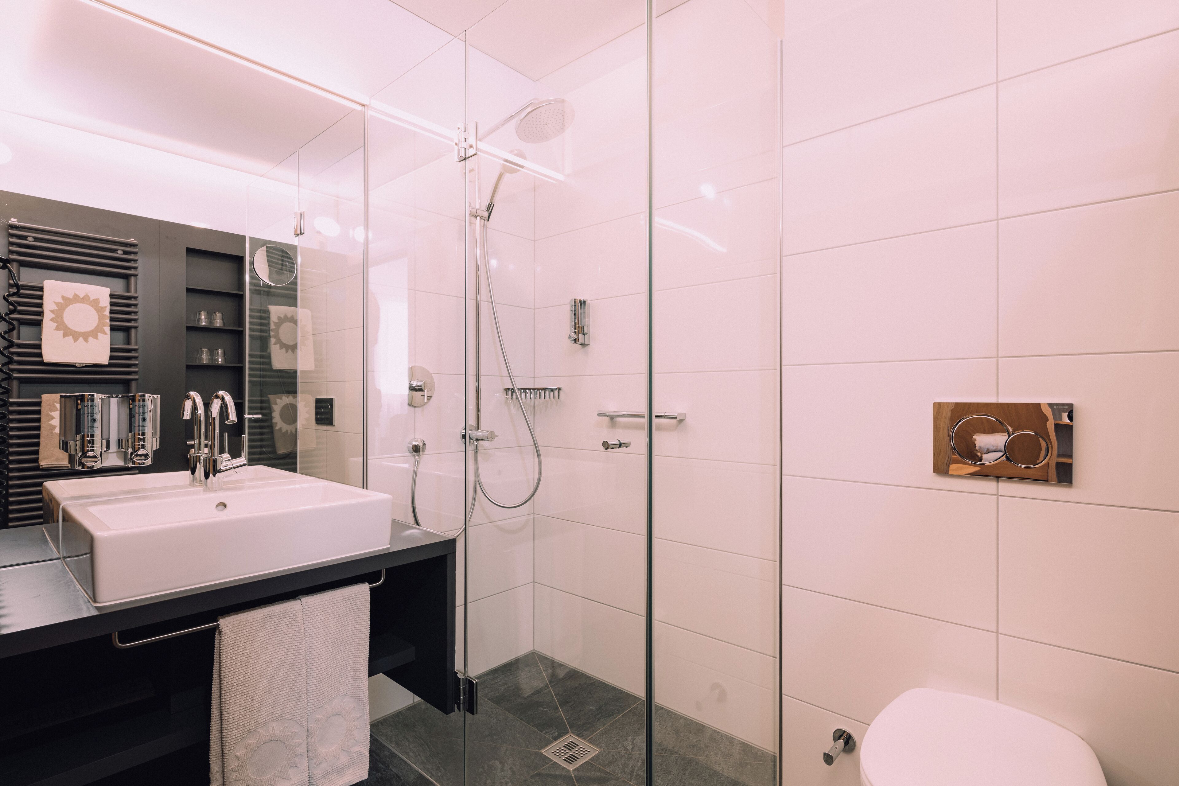 Un baño moderno con cabina de ducha de vidrio, un lavamanos blanco y un inodoro.