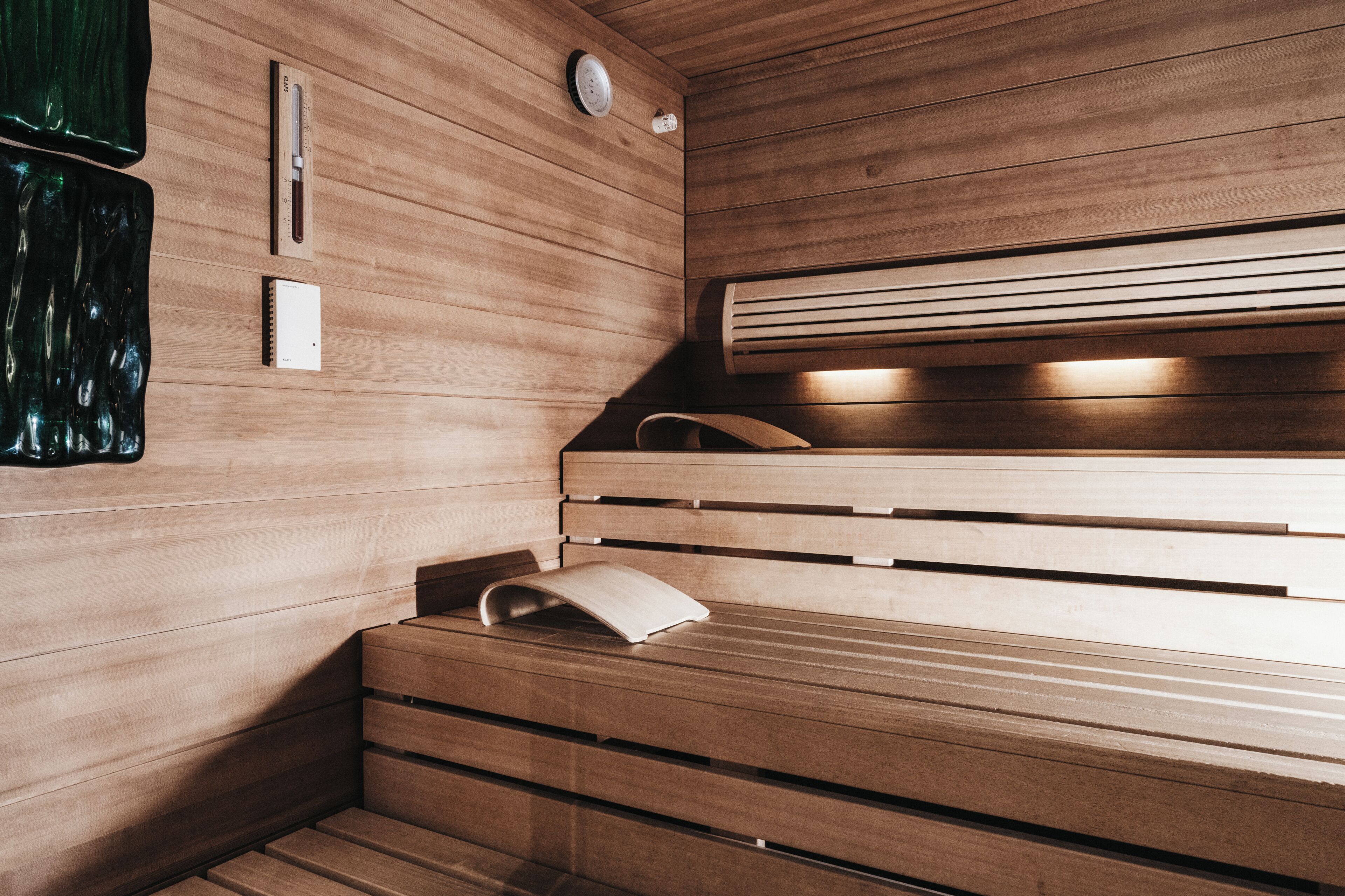 Una sauna con bancos de madera, un perchero para toallas y un termómetro en la pared.