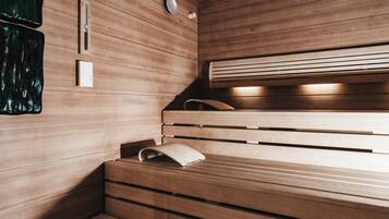 Una sauna con bancos de madera, un perchero para toallas y un termómetro en la pared.