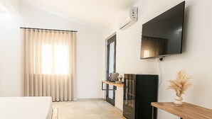 A hotel room with a bed, a desk, a chair, a TV, and a window with curtains. - Silenza B&B (Mattinata)