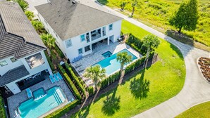A two-story house with a swimming pool, a patio, and a well-maintained lawn.