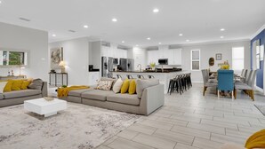 A modern living room with a sofa, coffee table, and a dining area with chairs and a table.