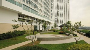 A modern hotel with a landscaped courtyard, a central circular feature, and a tall building in the background.