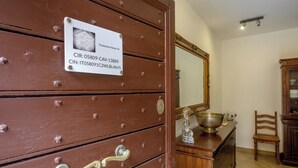 A brown wooden dresser with a metal plaque, a mirror, a bowl, and a chair in a room with wooden flooring. - Trastevere Home 14 Roma Centro, San Pietro, Gianicolo, American University. (Roma)