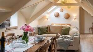 A cozy loft-style room with a dining area, a sofa set, and a dining table with chairs.