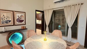 A dining area with a round table, six chairs, and a central light fixture. - Designer & Spacious 2BHK Private Suite (Islamabad)