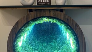 A framed artwork with a geometric design, a welcome sign for Airbnb, and a decorative bowl with a reflective surface. - Designer & Spacious 2BHK Private Suite (Islamabad)