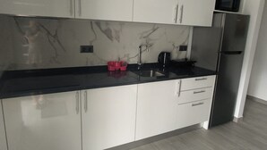 Una cucina moderna con mobili bianchi, un piano di lavoro nero e un frigorifero in acciaio inossidabile.