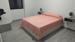 Una camera da letto con un letto, comodini, un tavolino e una pianta.
