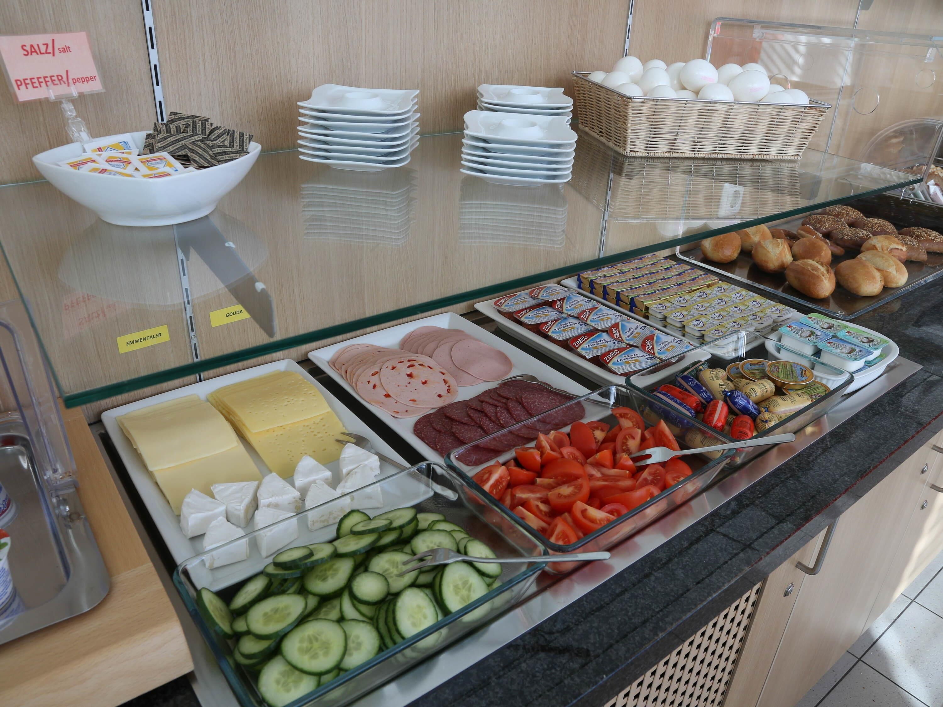 Een buffet met diverse gerechten, waaronder vleesschotels, kazen en groenten.