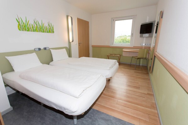 Una habitación de hotel con dos camas, un escritorio, una silla, un televisor y una ventana.