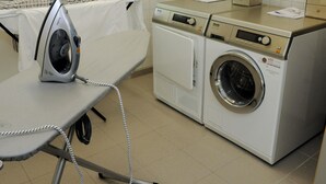 A laundry area with an ironing board, a washing machine, and a dryer. - Ibis Budget Augsburg City (Augsburg)