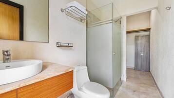 A modern bathroom with a large sink, toilet, and glass shower enclosure.