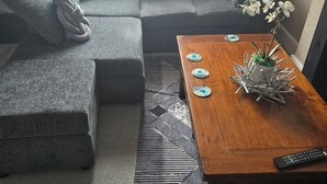 A living room with a grey sofa, a wooden coffee table, and a small plant. - Seaview 2 Double bed Apartment 2nd Floor (Llandudno)