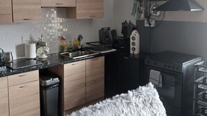 A modern kitchen with wooden cabinets, a black countertop, a stainless steel sink, a coffee maker, and a stove. - Seaview 2 Double bed Apartment 2nd Floor (Llandudno)
