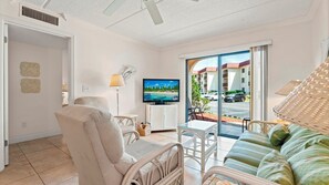 Un salon avec un téléviseur, un canapé, un fauteuil et une table.