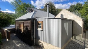 A small, single-story building with a sloped roof, a satellite dish, and a chimney. - Cosy cottage in the centre of historic Arrowtown (Arrowtown)