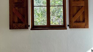 A room with a sloped ceiling, a window with wooden shutters, and a checkered bedspread. - Cosy cottage in the centre of historic Arrowtown (Arrowtown)