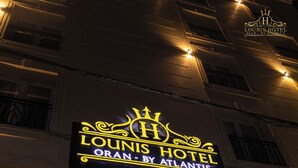 Un letrero de hotel con el nombre 'Lounis Hotel' y 'Oran by Atlantis', en inglés y en árabe.