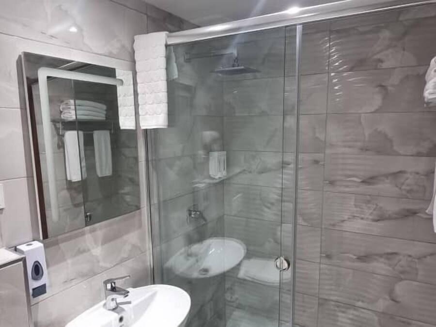 Un bagno moderno con doccia vetrata, lavandino bianco e porta asciugamani.