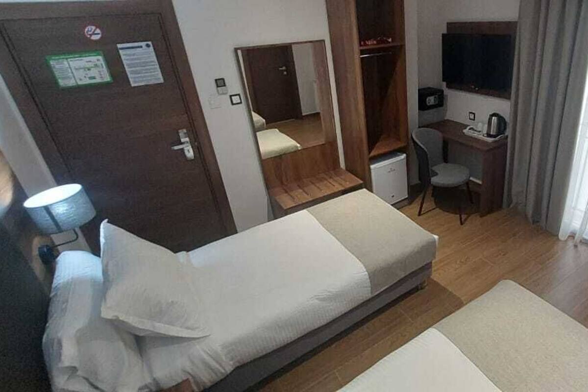 A hotel room with a bed, a desk, a chair, a TV, and a wardrobe.