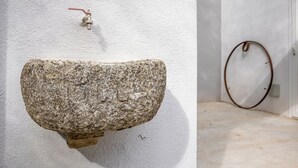 A stone sink mounted on a white wall with a red faucet. - ElChiMa by Wonderful Italy (Polizzi Generosa)