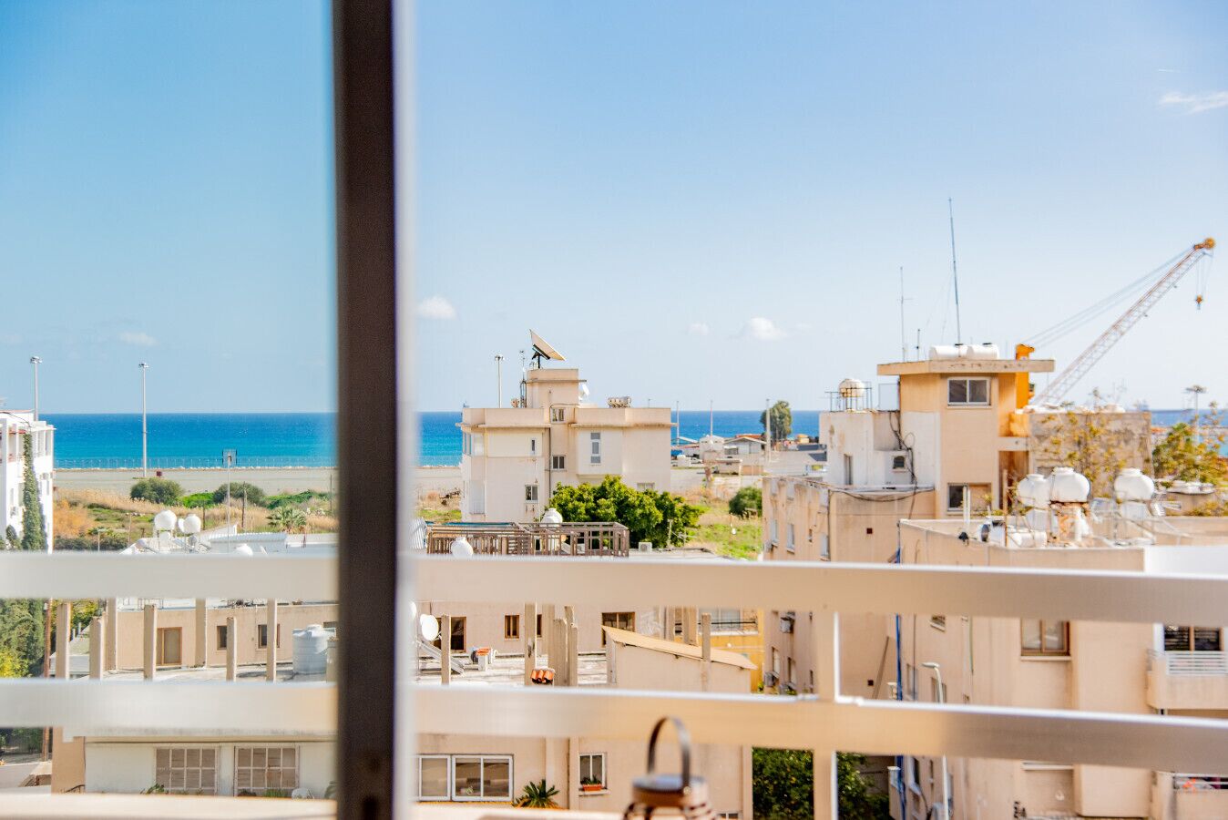 Zona residencial costera con edificios, una playa y una grúa.