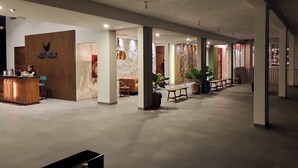 En rummelig lobby med receptionsdisk, siddeområde og en kombination af naturligt og kunstigt lys.