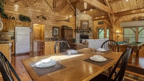 A rustic wooden cabin interior with a dining area, kitchen, and a pool table. - CABIN FEVER - Total Seclusion in Wears Valley! (Sevierville)