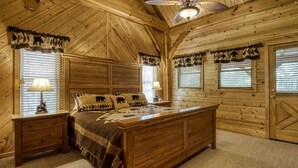 A log cabin bedroom with a wooden bed, two bedside tables, and a chandelier. - CABIN FEVER - Total Seclusion in Wears Valley! (Sevierville)