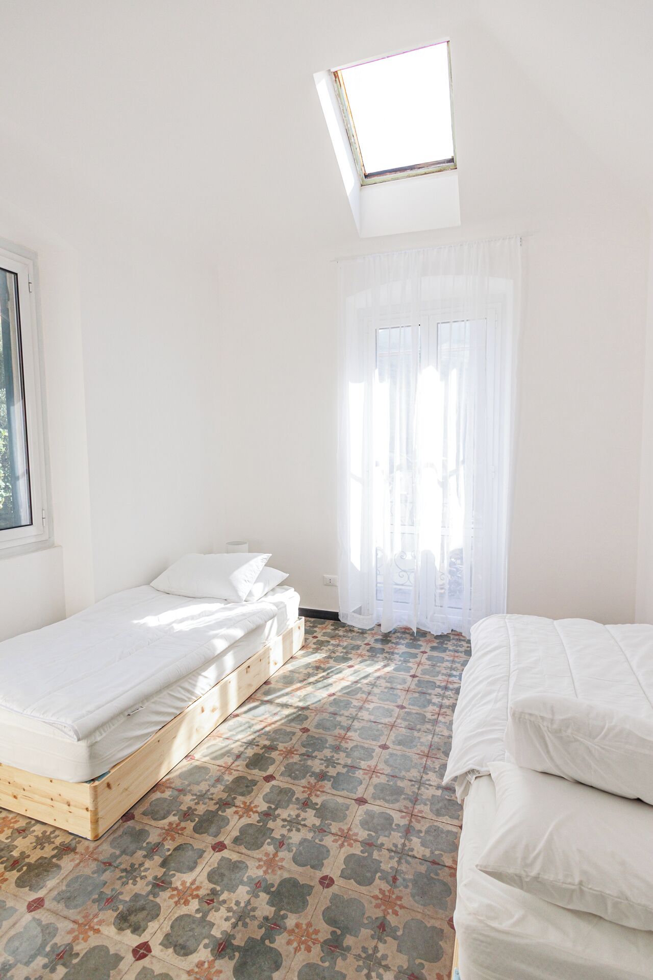Una habitación con tragaluz, una cama con estructura de madera y suelo estampado.