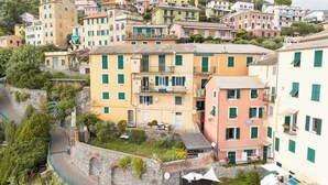 A multi-story building with balconies, a stone wall, and a narrow street. - Newly Renovated Ocean View Flat (Sori)