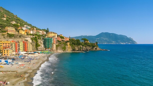 A coastal town with colorful buildings, a beach, and a mountain in the background. - Newly Renovated Ocean View Flat (Sori)