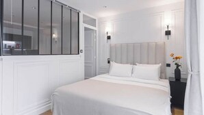 Un dormitorio moderno con una cama grande, un armario y una mesita de noche con un florero.