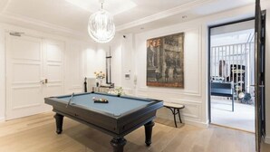 Una mesa de billar en una habitación con paredes blancas y un cuadro grande.