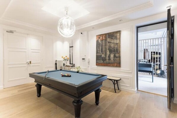 A pool table in a room with white walls and a large painting.