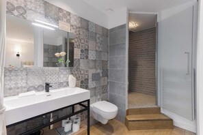 A modern bathroom with patterned tiles, a white sink, and a toilet.