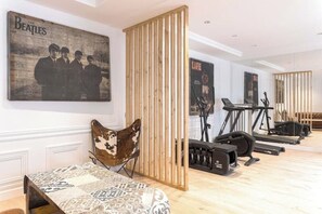 A room with a patterned bed, a wooden partition, a poster of The Beatles, and exercise equipment.