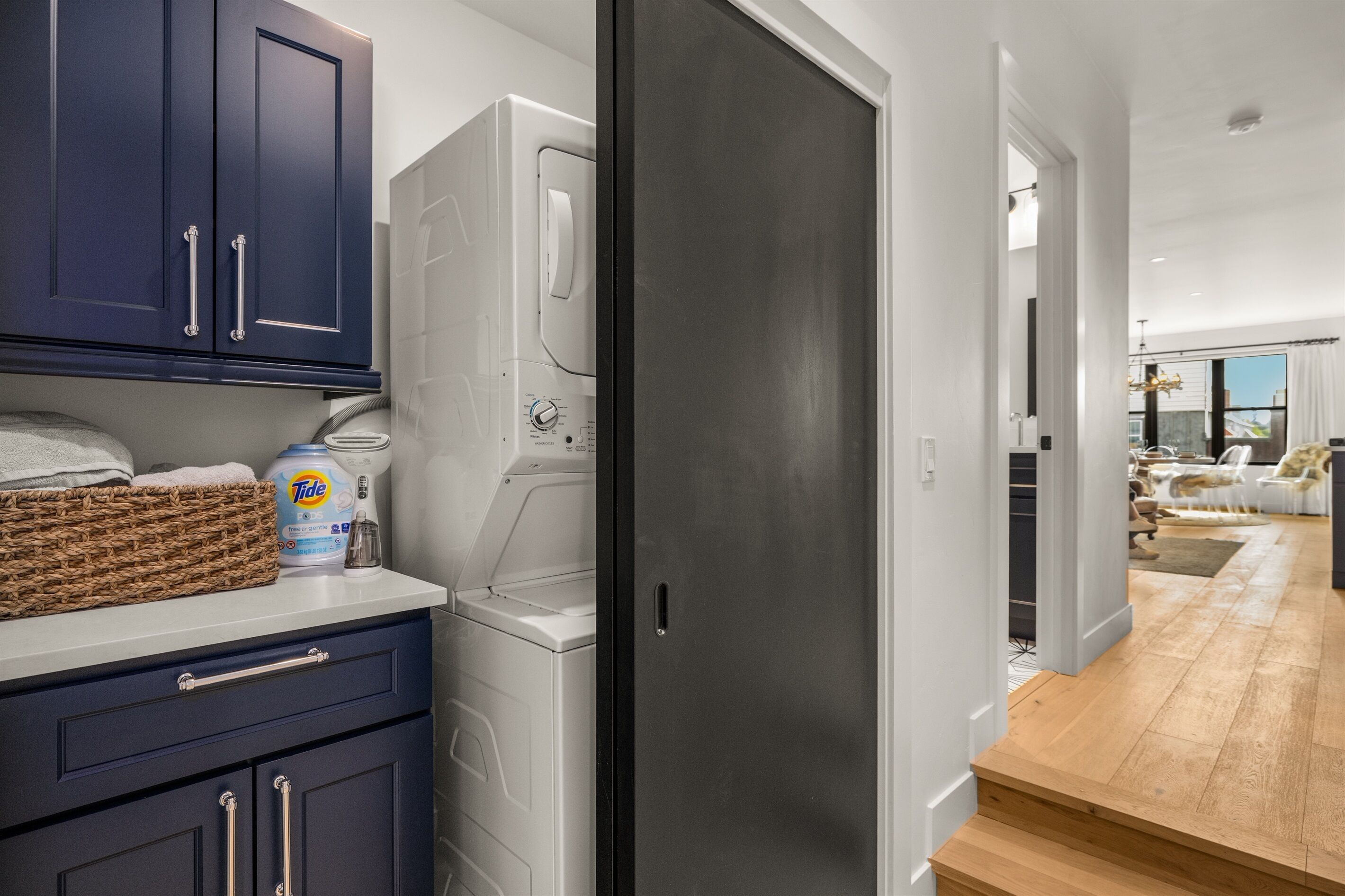 A laundry room with a washing machine, a basket, and a Tide detergent bottle.