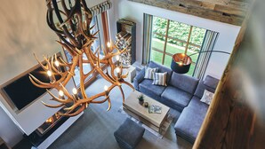 A modern living room with a large chandelier, a grey sofa, and a fireplace. - Atempause Sauerland feel-good chalet "Große Sehnsucht" (Schmallenberg)