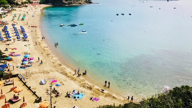 A beach with clear waters, umbrellas, and boats. - Casina di Nonna Meca by Solturelba (Capoliveri)