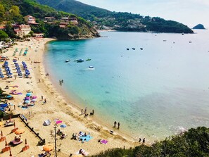 A beach with clear waters, umbrellas, and boats. - Casina di Nonna Meca by Solturelba (Capoliveri)