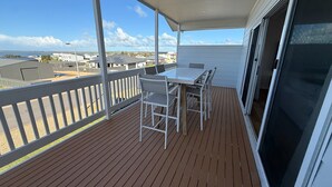 A balcony with a table and chairs, a view of buildings, and a clear sky. - Sea Escape - Sea Views!  Short walk to Tavern! Off Peak Special available! (Point Turton)